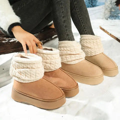 Tan winter boots with white textured trim worn by a person sitting on a snowy surface.