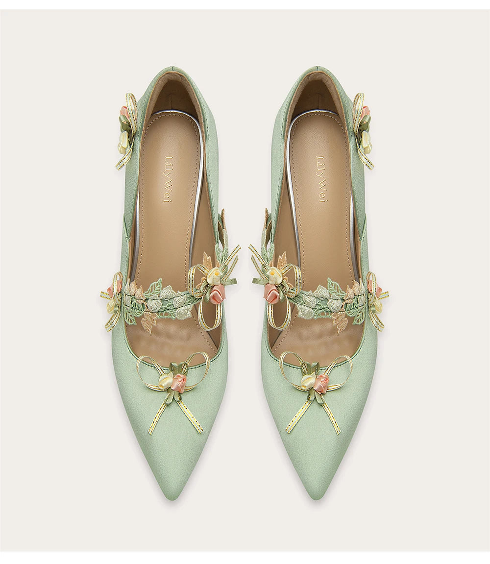 Pair of light green high heels with floral embellishments on a white background