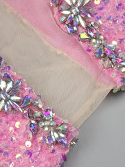 Close-up of pink fabric with sequin and bead embellishments on a neutral background
