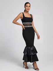 Model posing in a black pearl-embellished midi dress with satin ruffles.