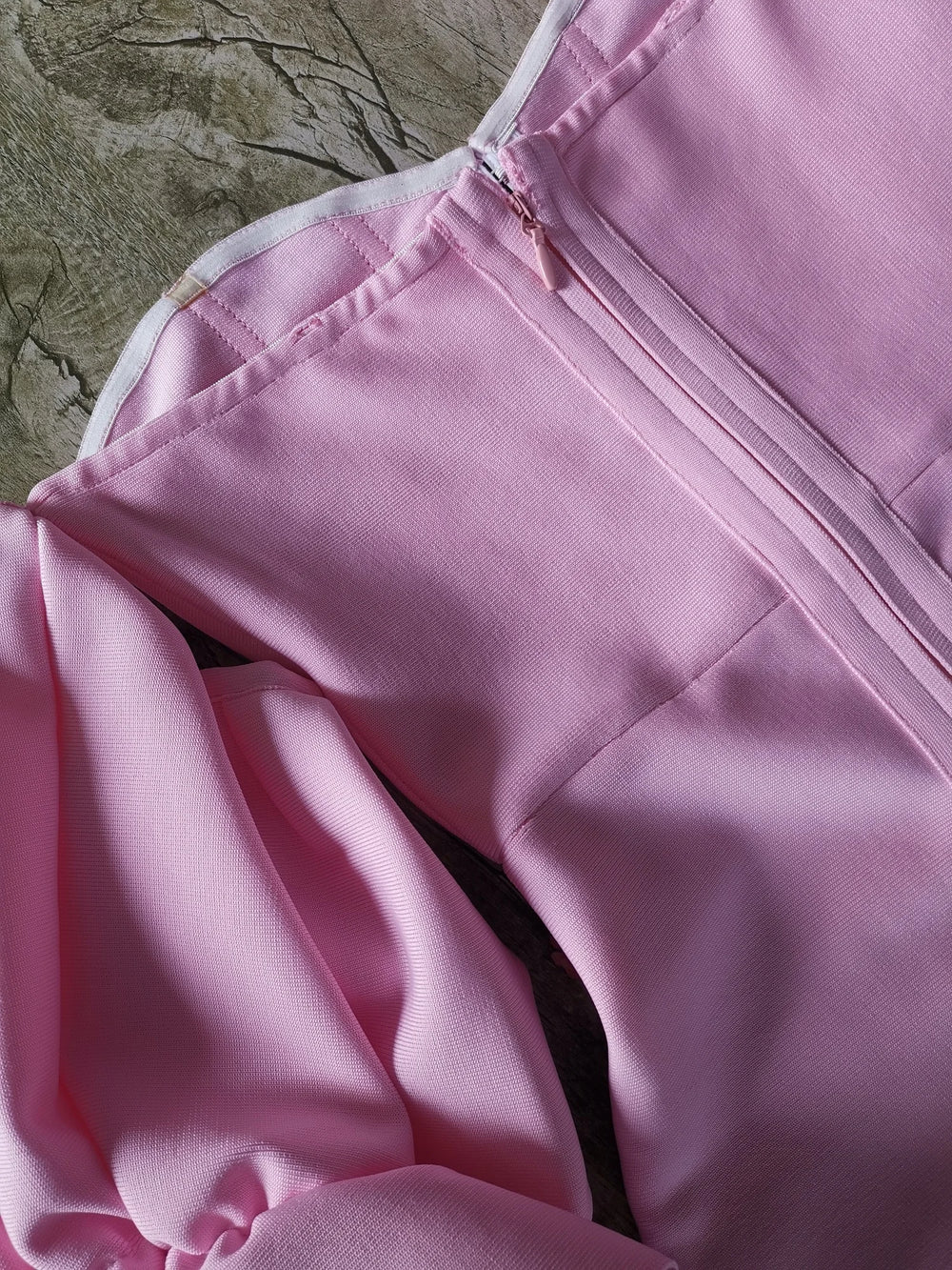 Close-up of a pink jacket with a zipper on a textured surface