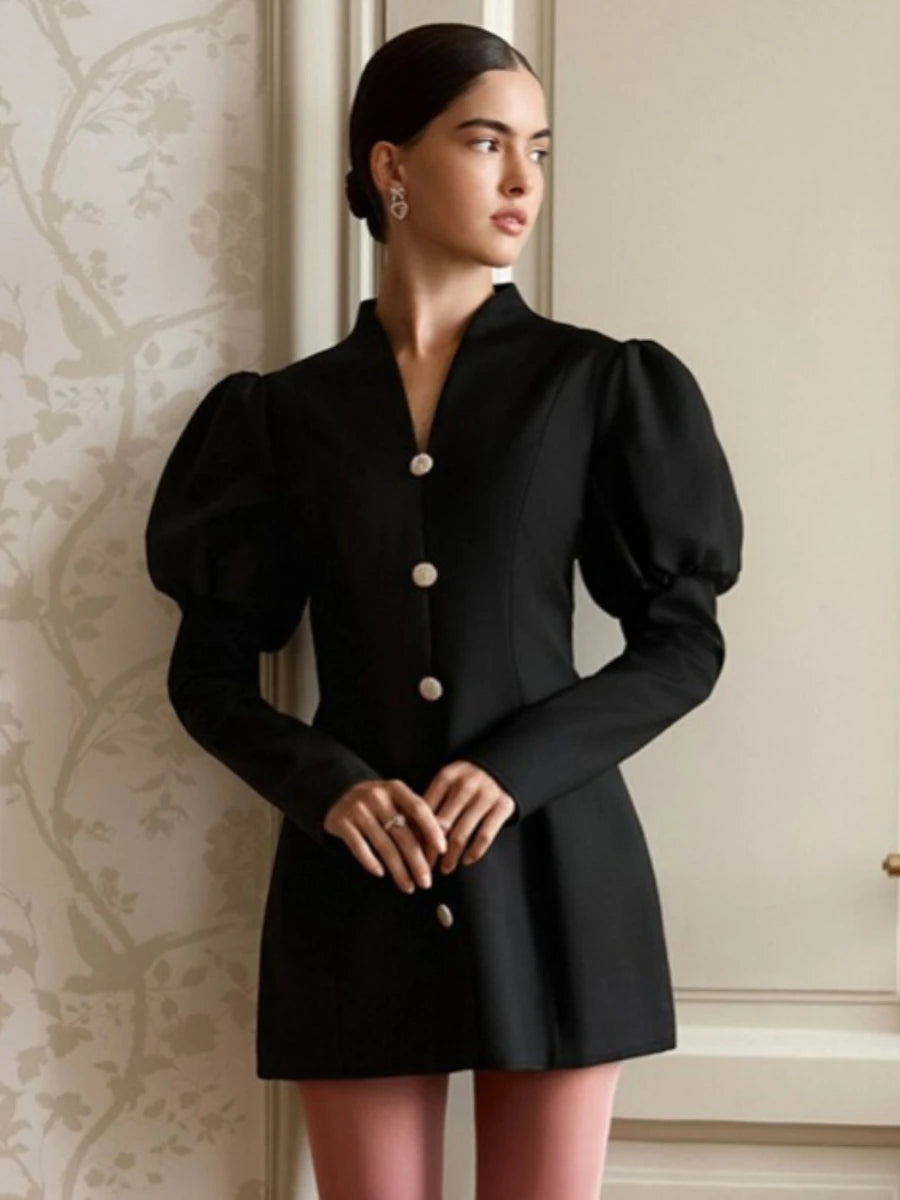 Woman wearing a black dress with puffed sleeves in an elegant interior setting