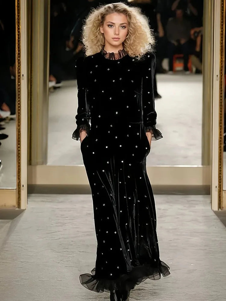 Model wearing a black dress with white embellishments on a runway.