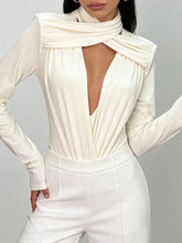Person wearing an apricot outfit with a deep neckline and high-waisted pants on a grey background