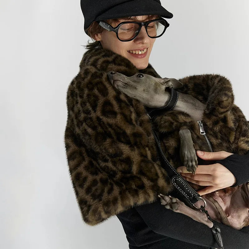 Person wearing a leopard print coat holding a dog on a white background