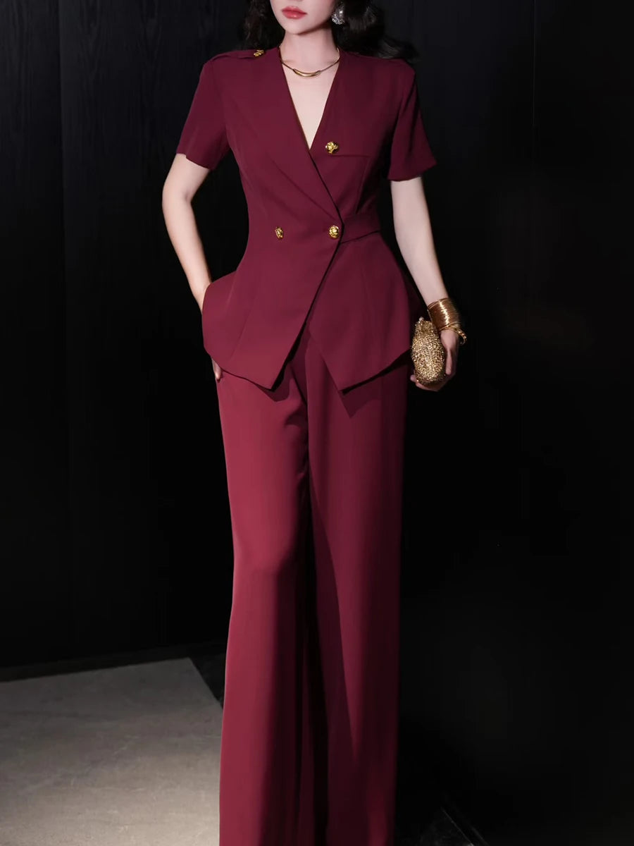 Woman wearing a burgundy suit with gold accents against a black background