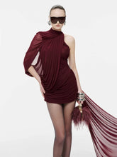 Woman wearing a burgundy dress with a feathered clutch against a white background