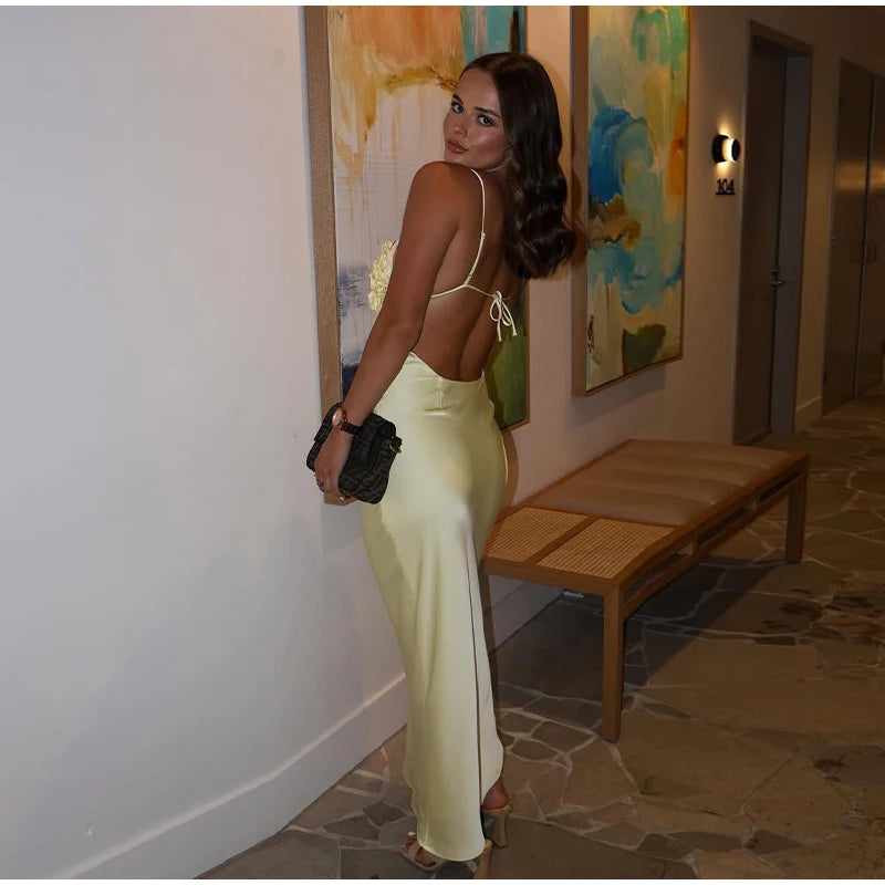 Woman in a yellow dress standing in a room with a bench and colorful artwork on the wall.