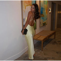 Woman in a yellow dress standing in a room with a bench and colorful artwork on the wall.