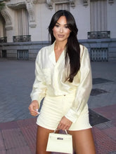 Woman in a white outfit standing on a street with a building in the background
