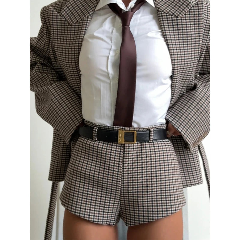 Person wearing a checkered suit with a white shirt and brown tie on a plain background