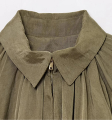 Close-up of a green garment with a collar and zipper on a white background