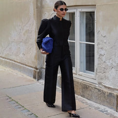 Woman in a black outfit holding a blue bag against a building background