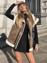 Woman wearing a brown shearling vest with white fur trim on a city street.