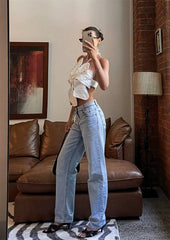Woman taking a mirror selfie in a stylish outfit in a living room.