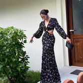 Woman in a floral dress standing outdoors next to a building