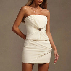 Woman wearing a strapless white dress with a decorative brooch against a neutral background