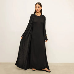 Woman wearing a black long-sleeve dress against a plain background