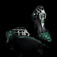 Black high-heeled shoes with green gemstones on a black background
