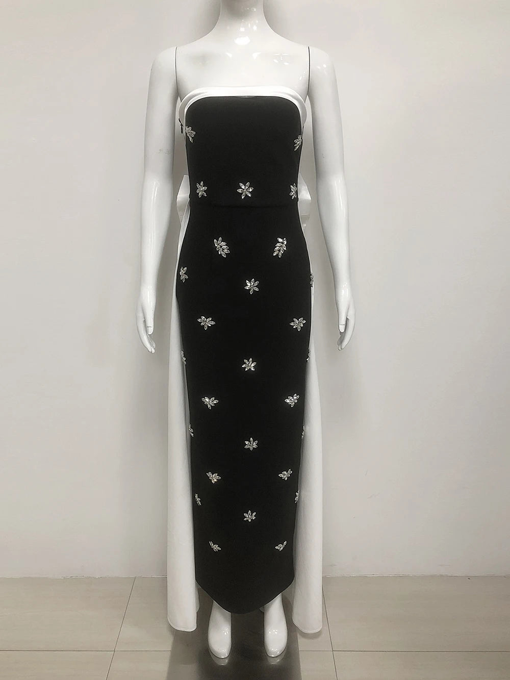 Black dress with white floral patterns on a mannequin against a white background