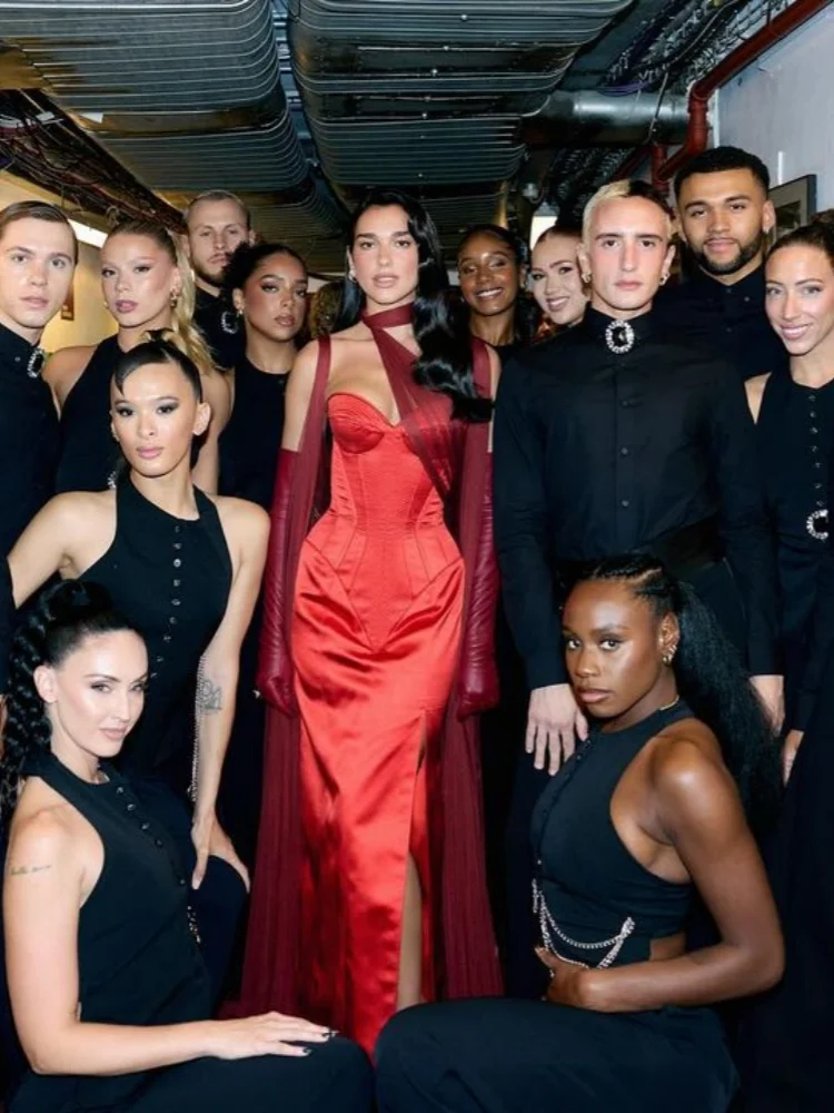 Group of people posing together, with a person in a red dress standing out.