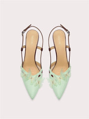 Pair of light green high-heeled shoes with decorative elements on a white background
