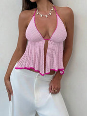 Woman wearing a pink crochet top with white pants against a plain background