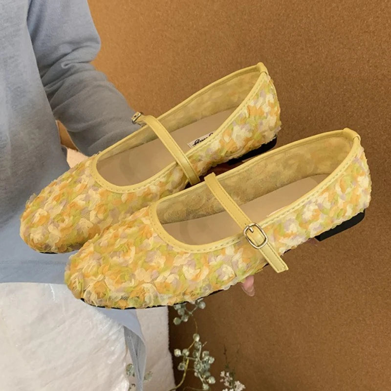 Yellow floral mesh Mary Jane flat shoes being held