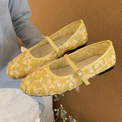 Yellow floral mesh Mary Jane flat shoes being held