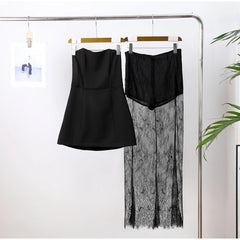 Black dress and black lace skirt hanging on a rack against a white wall.