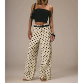Woman wearing a black strapless top and polka dot pants against a neutral background