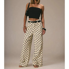 Woman wearing a black strapless top and polka dot pants against a neutral background