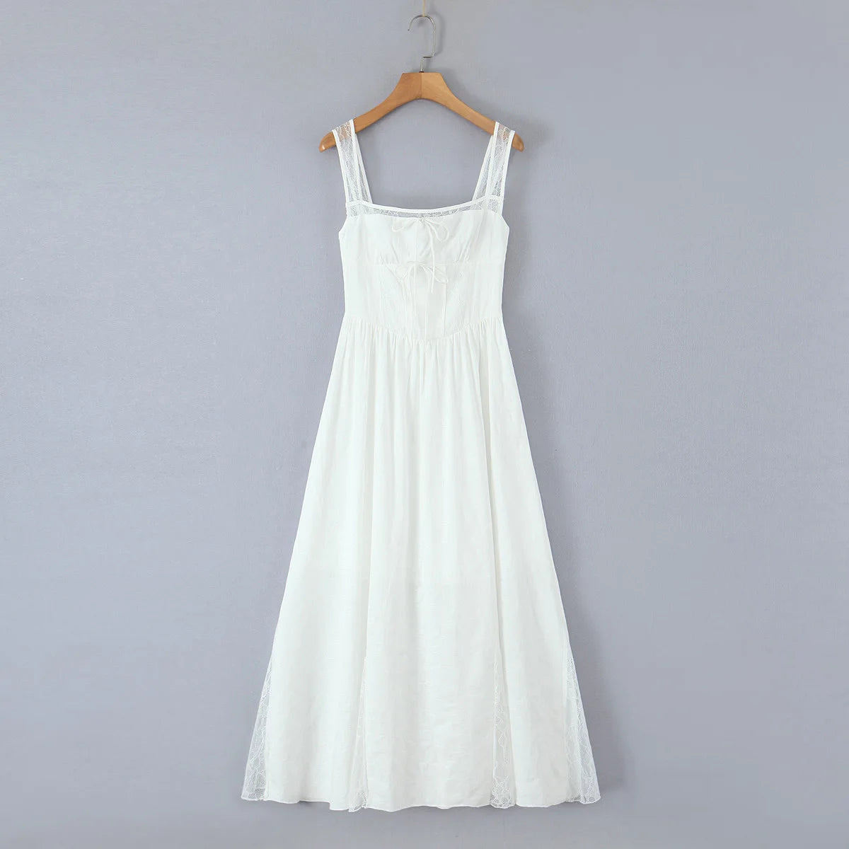 White dress on a wooden hanger against a gray background