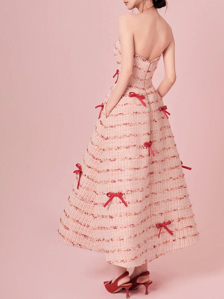 Woman wearing a strapless dress with red bows on a pink background