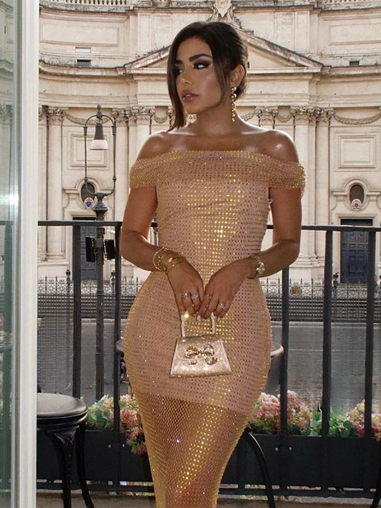 Woman in a gold off-shoulder dress standing in front of a building.