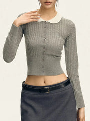 Woman wearing a gray ribbed sweater with a white collar and black skirt on a plain background