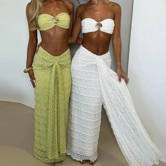 Two women wearing strapless tops and sarongs, one in green and the other in white, against a plain background.