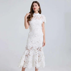 Woman wearing a white lace dress against a plain background