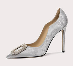 Silver high-heeled shoe with decorative buckle on a white background