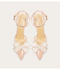 Pair of beige high-heeled shoes with bow details on a light gray background