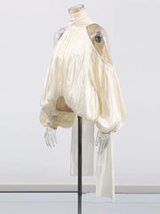 Mannequin wearing a flowing white garment on a plain background