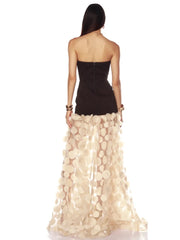 Woman wearing a black top and beige floral skirt on a white background