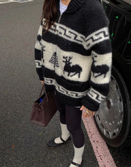 Person wearing a black and white patterned sweater with moose design, standing next to a car.