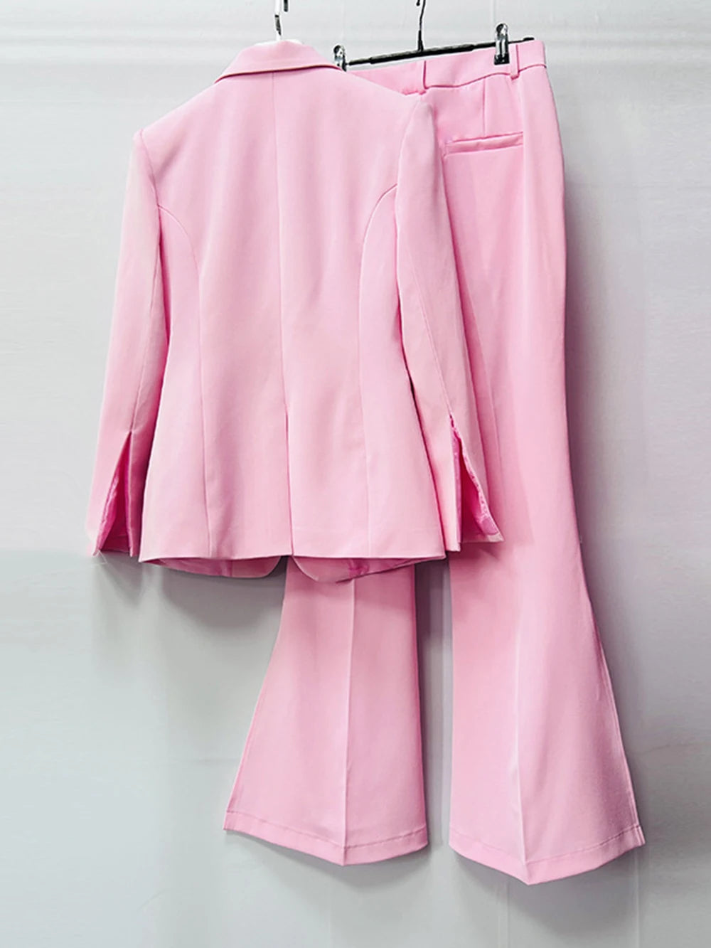 Pink single button blazer and split flare pants hanging from behind