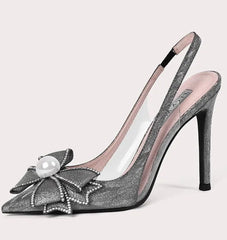 High-heeled shoe with decorative bow and pearl on a light gray background