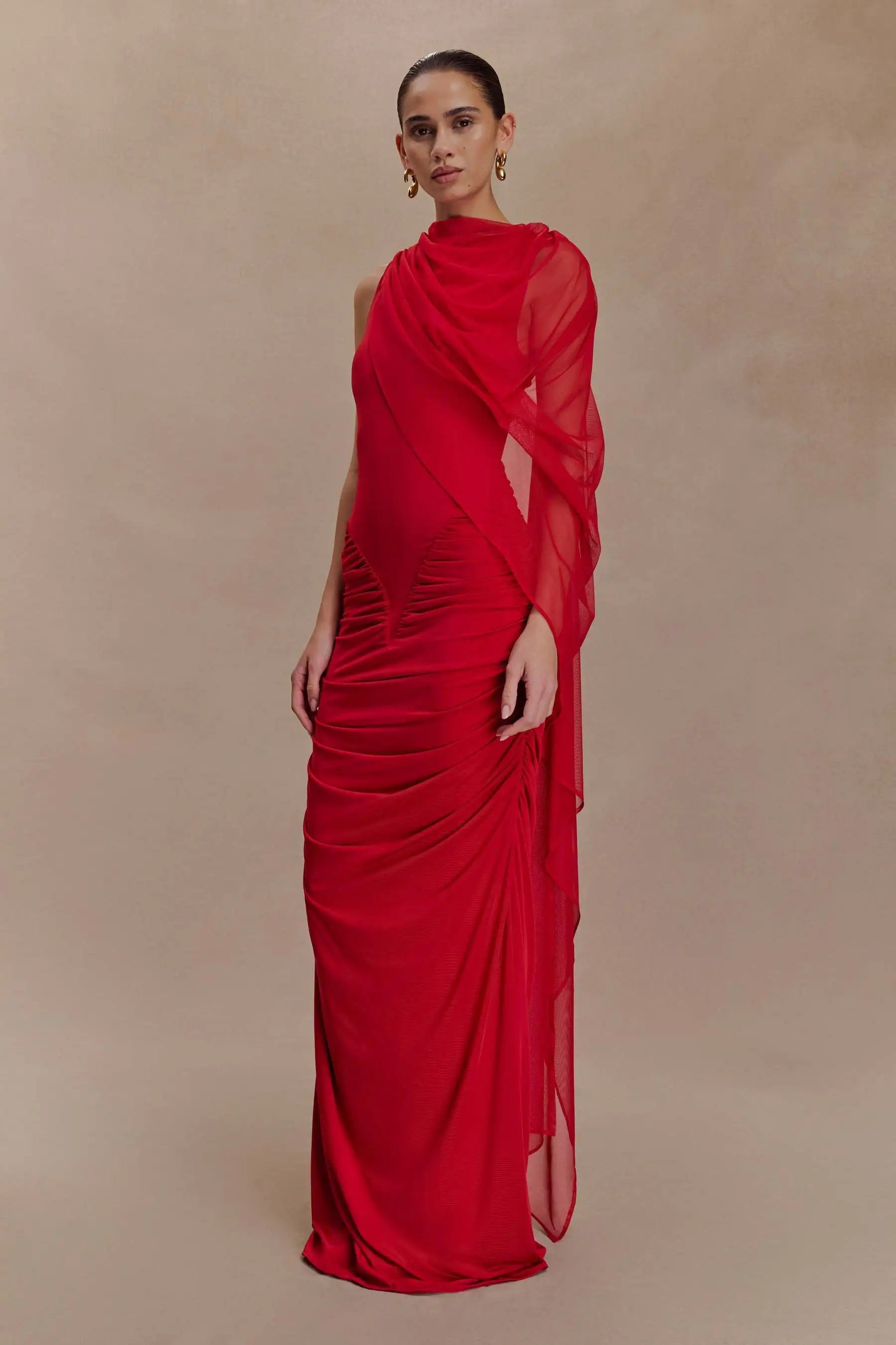 Woman wearing a red evening gown against a beige background