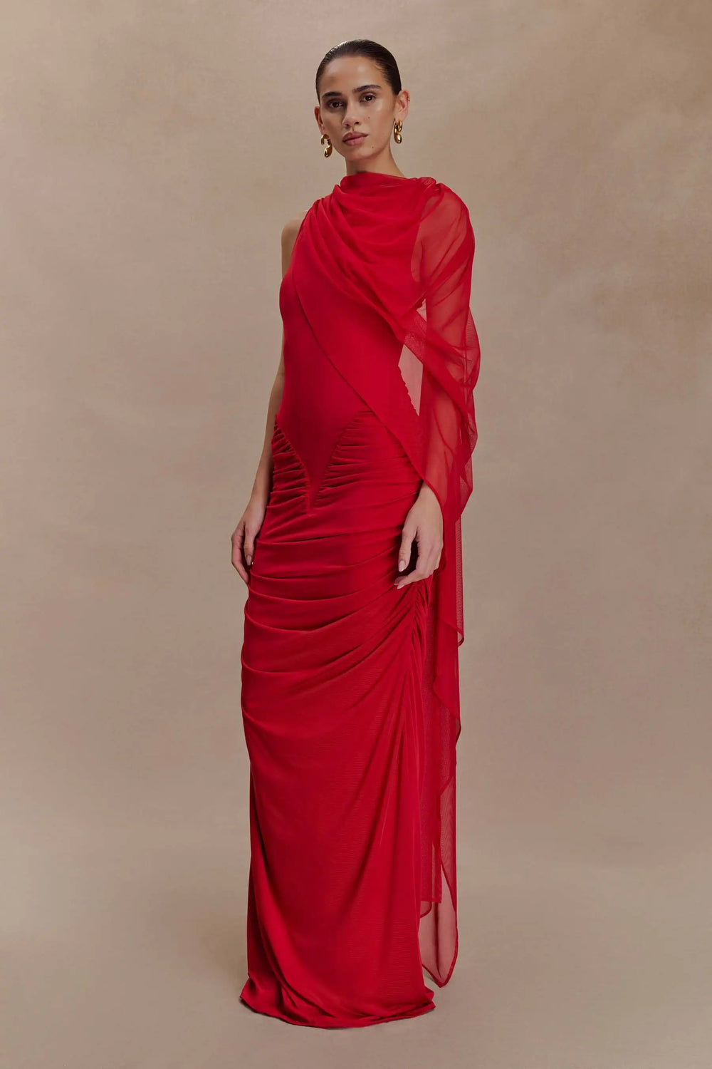 Woman wearing a red evening gown against a beige background
