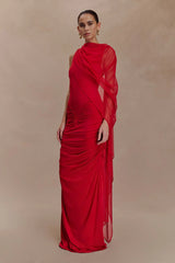 Woman wearing a red evening gown against a beige background