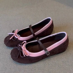 Pair of brown shoes with pink straps on a textured surface