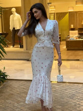 Woman in a white floral dress standing in an indoor setting